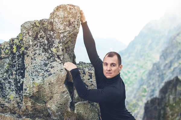 Young man makes hard climbing a steep rock without rope. — Stock Photo, Image