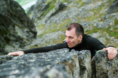 Genç adam halat olmadan dik kaya tırmanışı zorlaştırıyor.