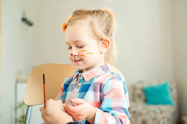 Mamá está pintando la cara de su hija como un gatito para el cumpleaños u otro evento de niños . — Foto de Stock