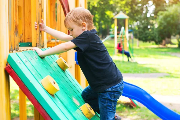 Bonito menino se divertindo e escalando no playground ao ar livre . — Fotografia de Stock