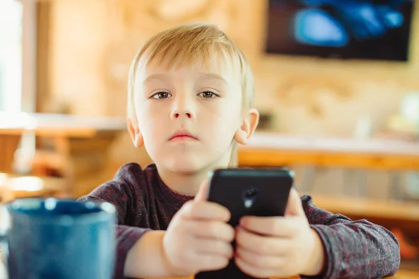 Söt liten pojke som spelar spel på smartphone hemma. — Stockfoto
