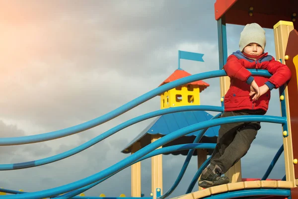 Netter Junge hat Spaß auf Spielplatz im Freien bei kaltem Wetter. — Stockfoto