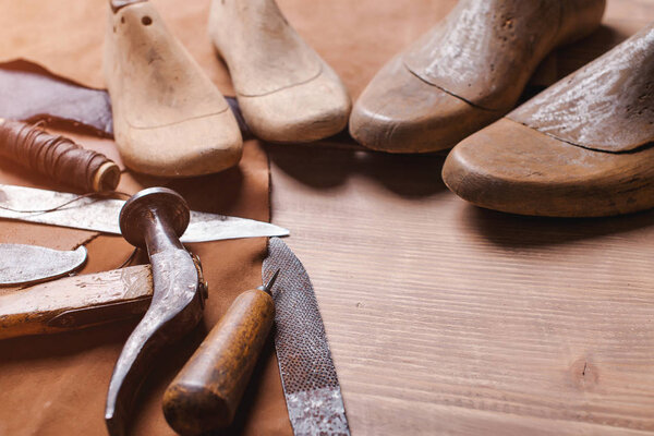 Cobbler tools in workshop on the wooden table . Space for text.