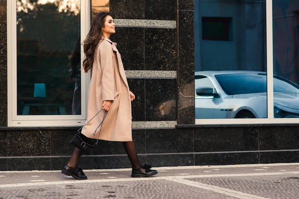 Молодая деловая женщина, идущая по городской улице перед современной стеной, вид сбоку . — стоковое фото