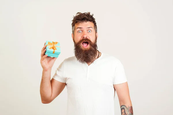 Impresionante hipster barbudo sosteniendo caja de regalo sobre fondo blanco. Sorpresa emociones hombre . — Foto de Stock