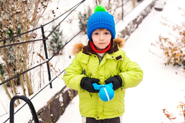 Népszerű játék gyerekeknek hógolyók készítéséhez. Gyerek játszik hó a parkban. Téli játékok szabadban. — Stock Fotó