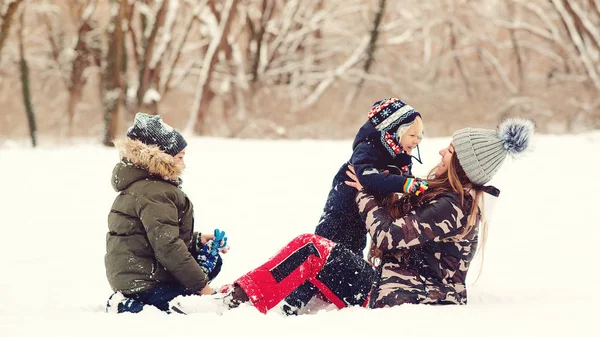 Niños encantadores y madre divirtiéndose juntos en la nieve en el parque. Invierno al aire libre juego. Vacaciones de invierno, vacaciones y estilo de vida . — Foto de Stock