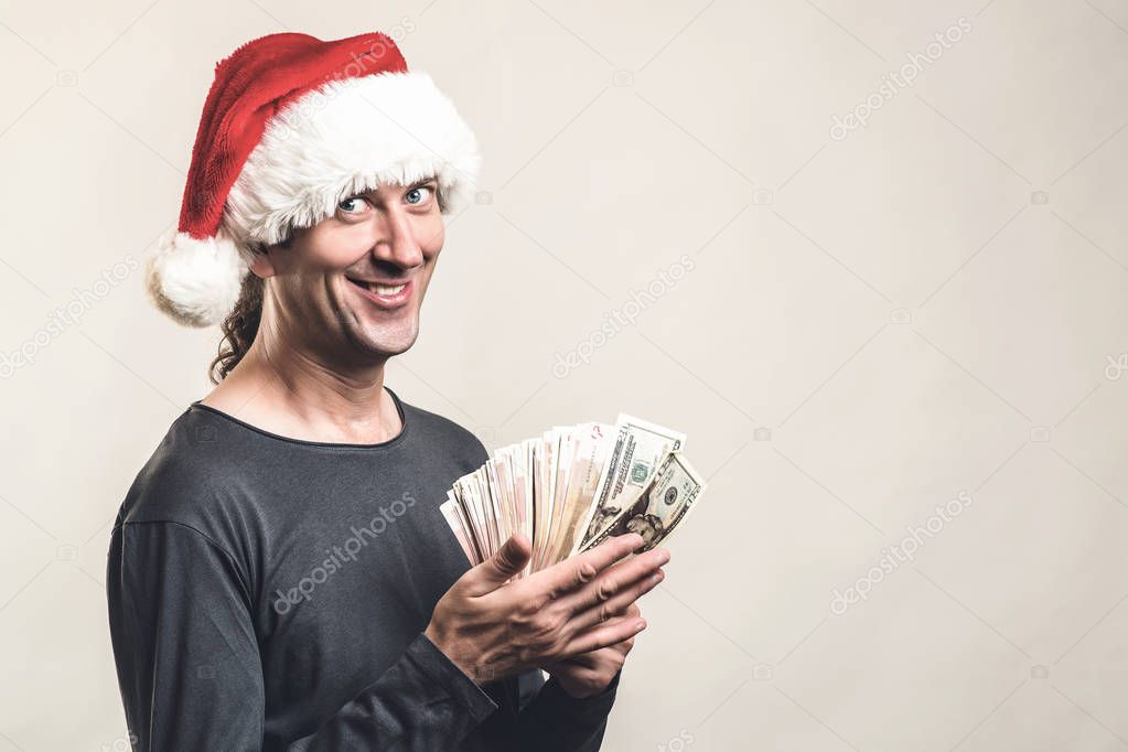 Handsome guy in Santa claus hat. Winning, currency and lifestyle concept. Happy excited holds fan of cash money. 
