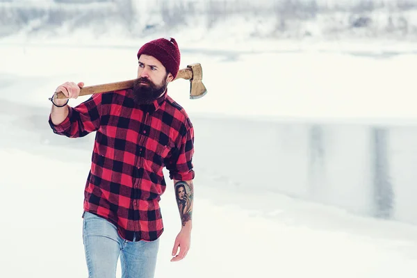 El leñador barbudo sostiene el hacha en invierno. Hombre brutal con ropa a cuadros de leñador . — Foto de Stock