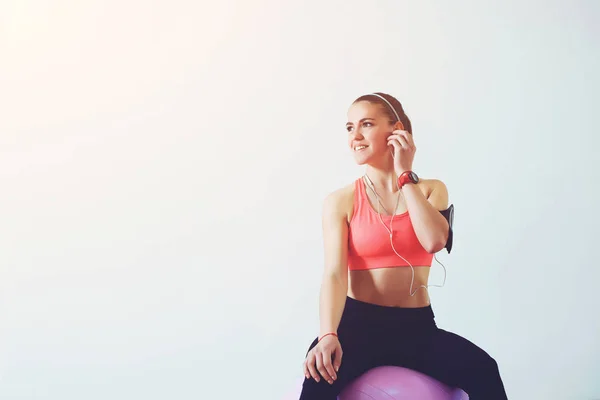 Femeia de fitness se relaxează după antrenament, stând pe o minge de fitness. Fată fericită în îmbrăcăminte de fitness relaxare după pilates . — Fotografie, imagine de stoc