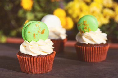 Açık havada krem peynirli ve bademli kurabiyelerle süslenmiş lezzetli kekler. Paskalya bayramı kartı. Sarı çiçek arka planında lezzetli kekler