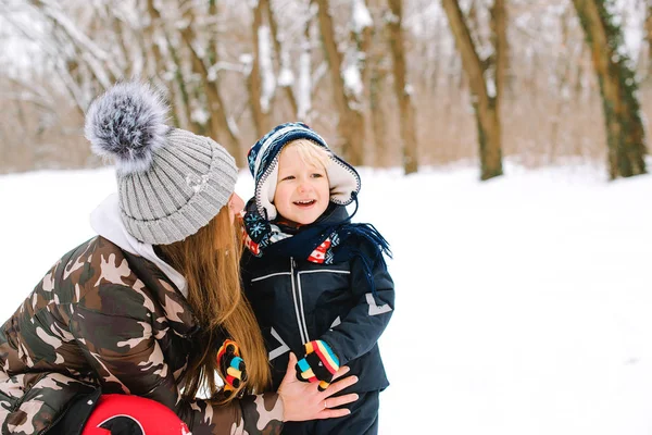 Happy mother and baby son in winter park. Little boy wearsknitted hat and scarf — Stock Photo, Image