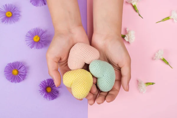 Vrouwelijke handen met kleurrijke harten.Kleurrijke papieren achtergrond met bloemen. Handverzorgingsconcept — Stockfoto