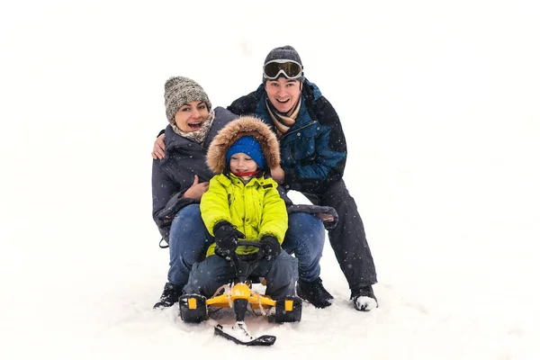 Happy family rides the sledge in winter. Winter vacation. Family having fun together in winter resort in mountain — Stock Photo, Image