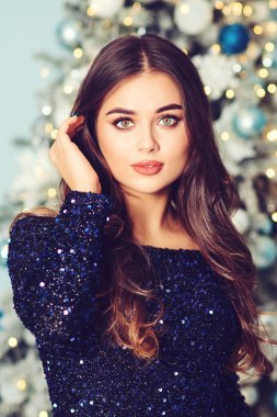 Şatafatlı kadın, Noel ağacı geçmişine karşı. Moda ve vuruşlar. Uzun saçlı, gece makyajlı, güzel bir kız.