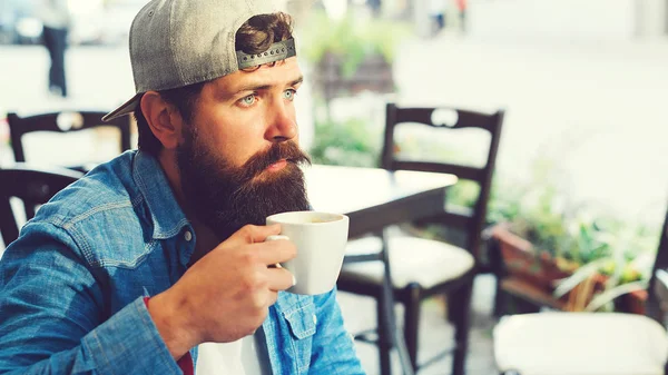 El guapo barbudo bebe café en la cafetería al aire libre. Hombre pensando y planeando día. Hipster tiene tiempo de descanso — Foto de Stock