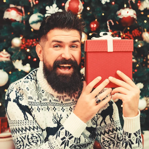 Skäggig kille som ler och håller julklapp. Trevlig vintersemester. God jul, då. — Stockfoto