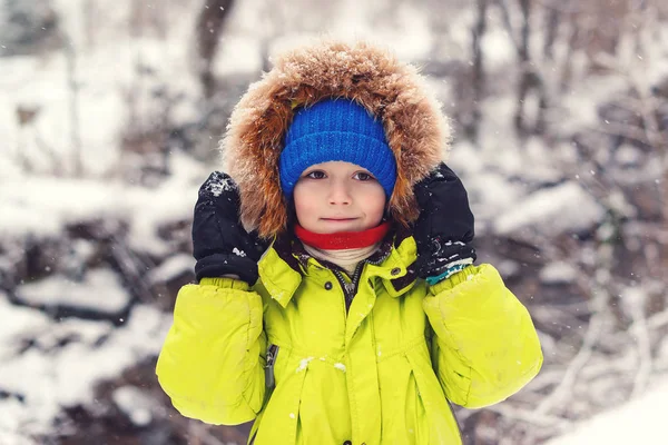 Aranyos kisfiú téli divatruhában. Gyermek egy téli séta a hóesés alatt. Téli vakáció — Stock Fotó