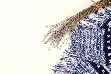 Beyaz arka planda örülmüş kadın kazakları ve kurutulmuş lavanta. Üst görünüm, kopyalama alanı ile