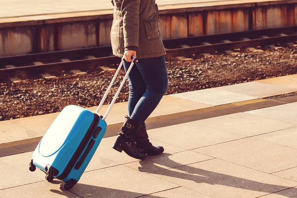 Menina arrastando mala de bagagem azul. Conceito de viagem. Mulher na estação de comboios. Férias felizes — Fotografia de Stock