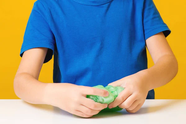 Gelukkige jongen maakt een slijm, close-up. Zelfgemaakte populaire speelgoedslijm. Kind speelt met slijm — Stockfoto