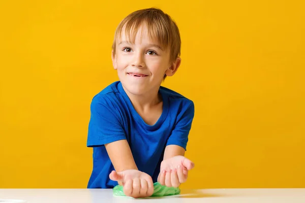 Glücklicher Junge macht Schleim am Tisch. hausgemachter beliebter Spielzeugschleim. Kind spielt mit Schleim — Stockfoto