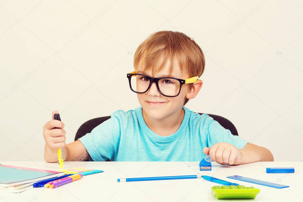 Little student boy studying and reading books at class. Cute school boy with eyeglasses doing homework