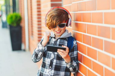 Akıllı telefon kullanan ve dışarıda oyun oynayan duygusal çocuk. Oğlan evet işareti yapıyor. Teknoloji ve iletişim. Çocuk arkadaşlarıyla internette oyun oynuyor..