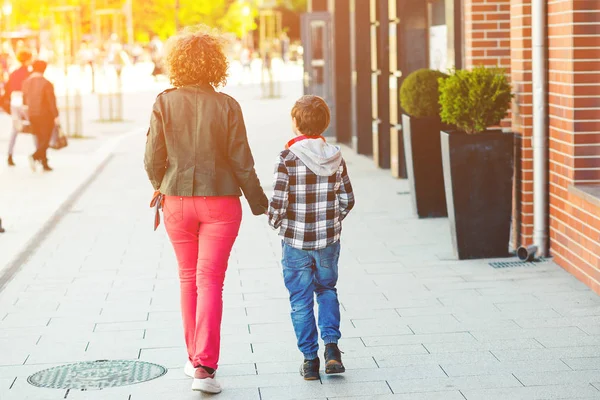 Mutlu anne ve oğul şehir caddesinde yürüyor, arka manzara. Aile, annelik ve ilişki