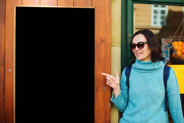Une voyageuse pointant vers un panneau d'affichage noir vide. Étudiante marchant dans la rue. Marché de rue — Photo