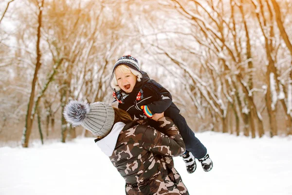 Feliz madre e hijo bebé divirtiéndose juntos en el parque de invierno. Preciosa familia jugando con nieve y caminando al aire libre. Feliz y saludable infancia — Foto de Stock