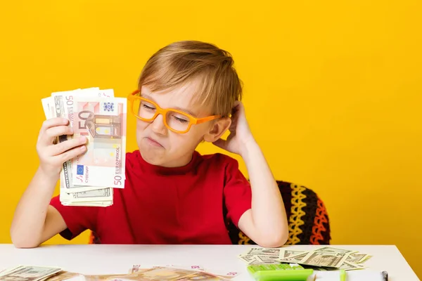 Para kazanmak için nereye yatırım yapacağını düşünen küçük bir çocuk. Çocukların finansal okur yazarlığı — Stok fotoğraf