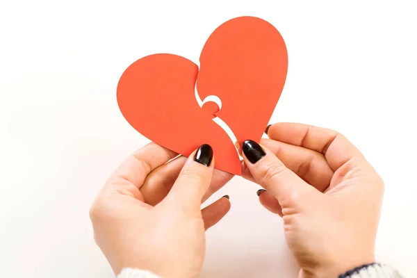 Kvinna försöker koppla ihop två delar av ett brustet hjärta, ovanifrån. Alla hjärtans dag. Kärlek, relation, skilsmässa. — Stockfoto