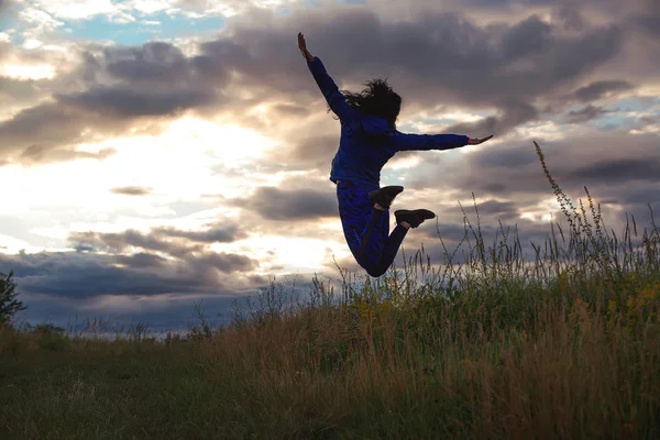 Спортивна жінка стрибає з відкритими руками на відкритому повітрі. Дівчина в спортивному одязі займається фізичними вправами на природі. Успіх і цілі — стокове фото