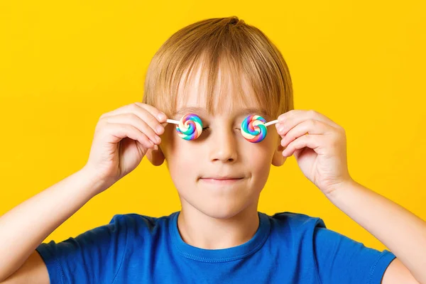 快乐的孩子用两片五颜六色的棒棒糖遮住眼睛. 快乐健康的童年 — 图库照片