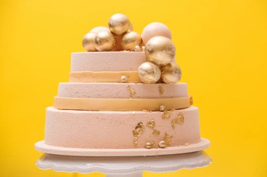 Altın toplarla süslenmiş katlı doğum günü pastası. Düğün için süslemeli pasta ya da sarı arka planda yıldönümü