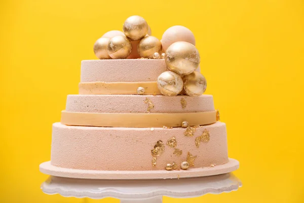 Pastel de cumpleaños estratificado decorado con bolas de oro. Pastel decorado de lujo para boda o aniversario sobre fondo amarillo — Foto de Stock