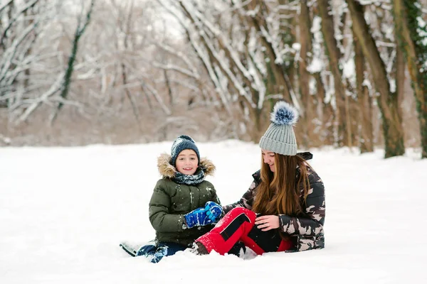Happy christmas vacation. Young mother and son having fun in winter park. Family playing with snow outdoors — Stock Photo, Image