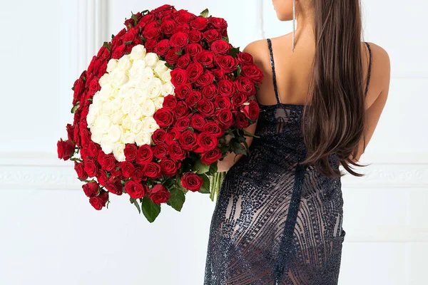 Mujer sexy sosteniendo un gran ramo de rosas. Feliz día de San Valentín. Chica de moda de lujo en vestido de noche. Sensual mujer vista trasera — Foto de Stock