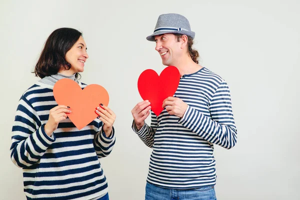 Усміхнений чоловік і жінка тримають два червоних паперових серця. З днем Святого Валентина. Сім'я, стосунки і любов — стокове фото