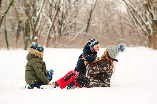 Lovely family playing with snow in park. Happy kids and mother having fun together outdoors — Stock Photo, Image