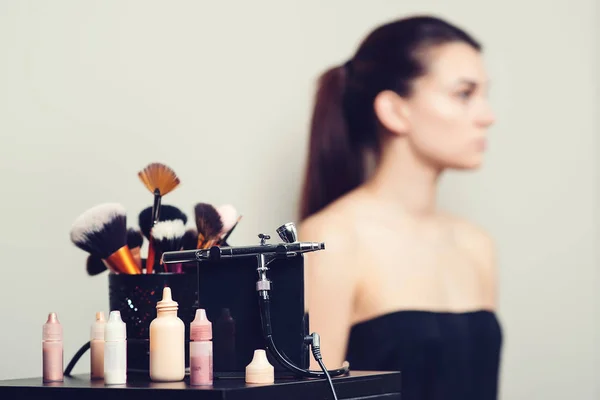 Maquillaje artista herramientas preparadas para el trabajo. Conjunto de cosmética y aerógrafo sobre fondo visagiste lugar de trabajo — Foto de Stock