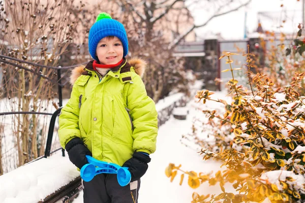 Speels jongetje dat sneeuwballen maakt in de achtertuin. Kind speelt buiten met sneeuw. Wintervakantie — Stockfoto
