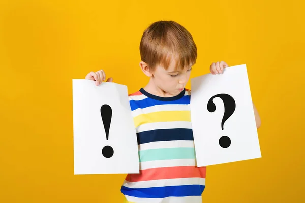 Kluge Schüler rätseln über Fragezeichen und Ausrufezeichen. Denkender Junge auf gelbem Hintergrund. — Stockfoto