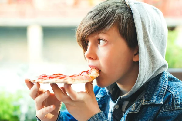 Hladový chlapec jí pizzu. Školák obědvá o přestávce — Stock fotografie