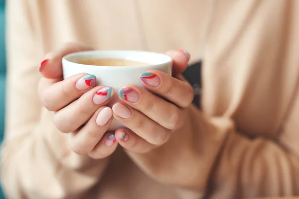 Las mujeres manos con uñas de moda de arte. Chica sosteniendo una taza de café blanco, primer plano. Cafetería. Humor matutino . — Foto de Stock