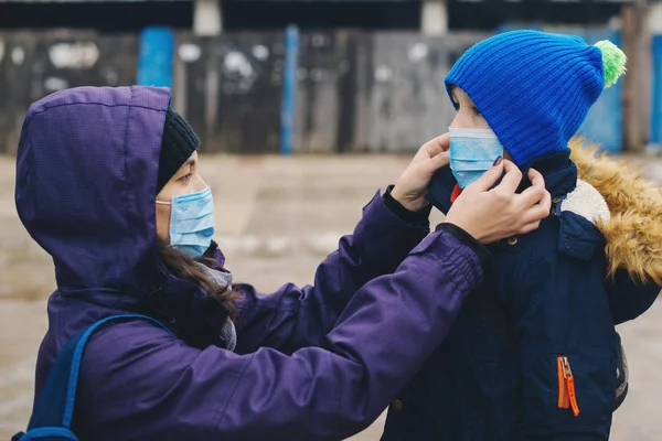 Mutter legt ihrem Kind eine Gesichtsschutzmaske auf die Straße. Beenden Sie die Infektion. Coronavirus-Quarantäne. Apokalypse. — Stockfoto