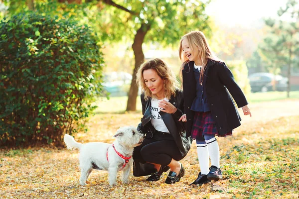 Jovem mãe e sua filha brincando com o cão ao ar livre. Família, animal de estimação, animal doméstico e conceito de estilo de vida. Hora do Outono — Fotografia de Stock