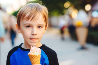Cute boy eating ice cream at the city centre. Happy and healthy childhood. Kid enjoying tasty fruit ice-cream.