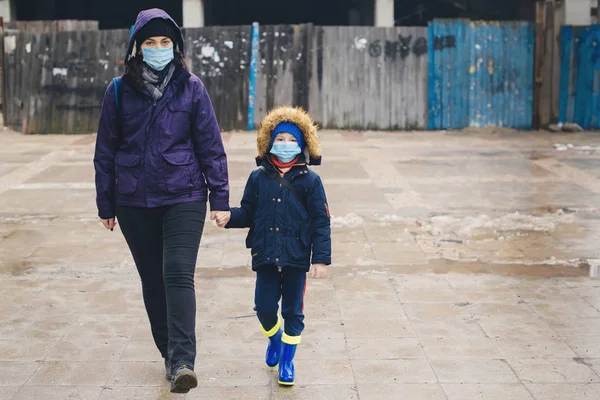 Мати і син йдуть по вулиці в захисних масках для обличчя. Квартал — стокове фото